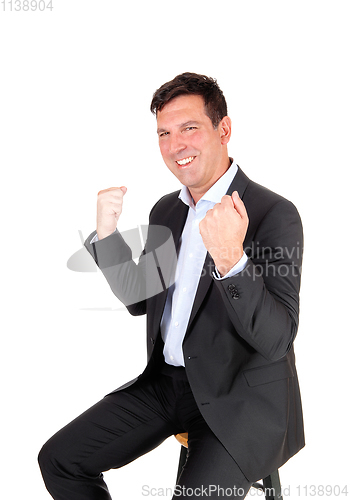 Image of Man sitting on chair with hands in fist, victory