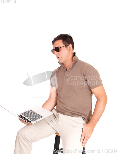 Image of Middle age man sitting on a chair with laptop