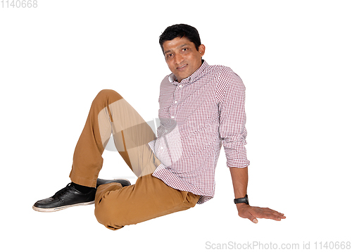 Image of Relaxed East Indian man sitting on floor