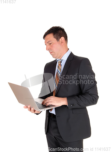 Image of Business man reading on his laptop and standing