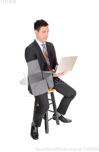Image of Happy businessman sitting with his laptop