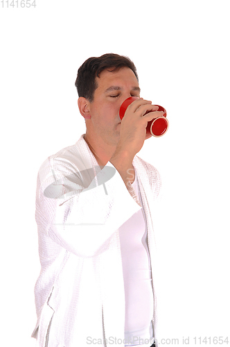 Image of Tall man standing in bathrobe drinking coffee 