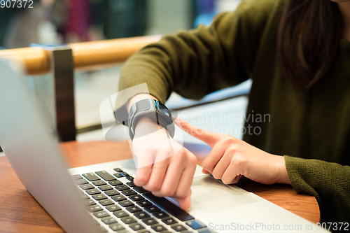 Image of Woman connecting smart watch on laptop computer