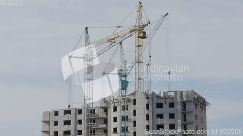 Image of Many of cranes. Tower cranes against blue sky, with clouds