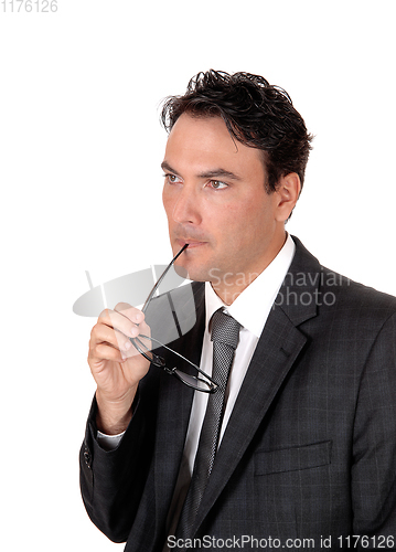 Image of Businessman thinking with glasses in his mouths