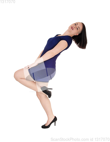 Image of Woman standing in a blue tight dress bending backwards