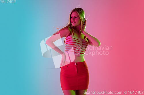 Image of Beautiful girl in fashionable, romantic outfit on bright gradient pink-blue background in neon light