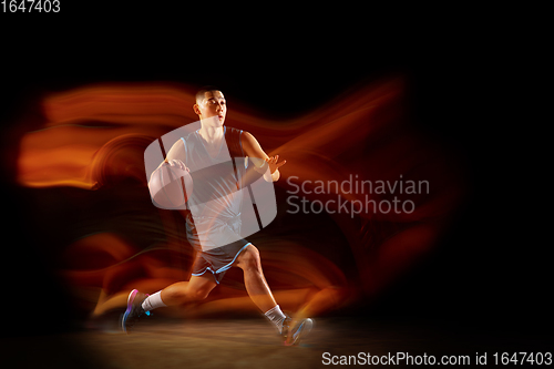 Image of Young east asian basketball player in action and jump in mixed light over dark studio background. Concept of sport, movement, energy and dynamic, healthy lifestyle.