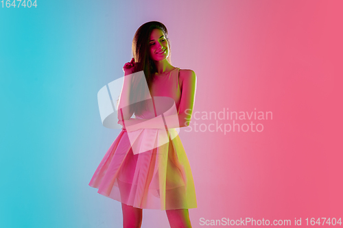 Image of Beautiful seductive girl in fashionable, romantic outfit on bright gradient pink-blue background in neon light