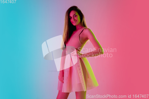 Image of Beautiful seductive girl in fashionable, romantic outfit on bright gradient pink-blue background in neon light