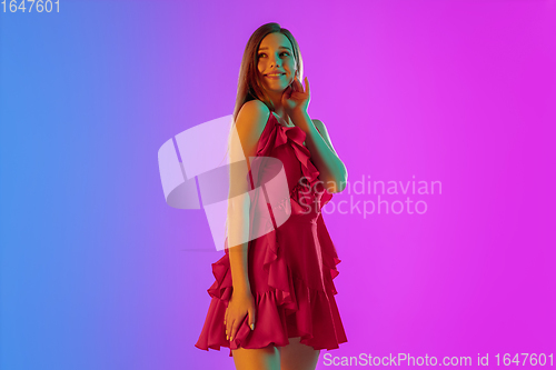 Image of Beautiful seductive girl in fashionable, romantic outfit on bright gradient purple-blue background in neon light