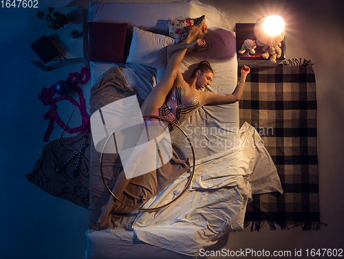 Image of Top view of young professional rhythmic gymnast sleeping at her bedroom in sportwear with hoola hoop.