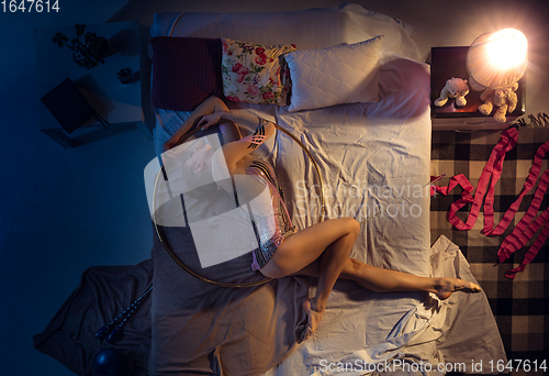 Image of Top view of young professional rhythmic gymnast sleeping at her bedroom in sportwear with hoola hoop.