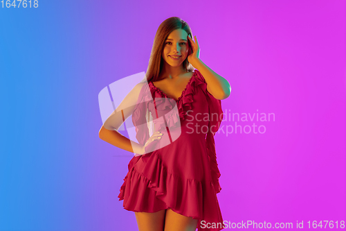Image of Beautiful seductive girl in fashionable, romantic outfit on bright gradient purple-blue background in neon light