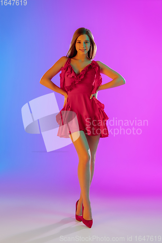 Image of Beautiful happy girl in fashionable, romantic outfit on bright gradient purple-blue background in neon light