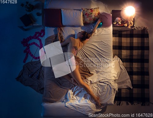 Image of Top view of young professional rhythmic gymnast sleeping at her bedroom in sportwear with ribbon.