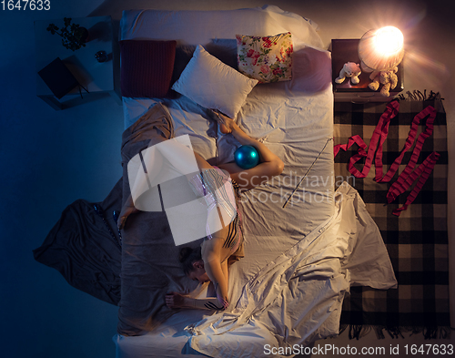 Image of Top view of young professional rhythmic gymnast sleeping at her bedroom in sportwear with blue ball.