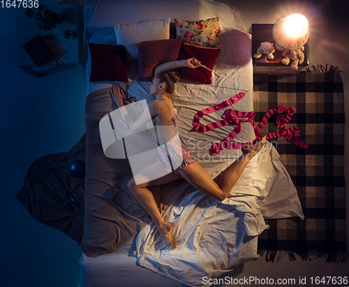 Image of Top view of young professional rhythmic gymnast sleeping at her bedroom in sportwear with ribbon.