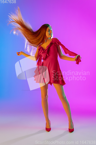 Image of Beautiful happy girl in fashionable, romantic outfit on bright gradient purple-blue background in neon light