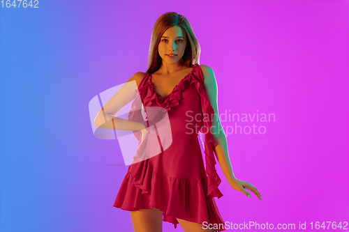 Image of Beautiful seductive girl in fashionable, romantic outfit on bright gradient purple-blue background in neon light