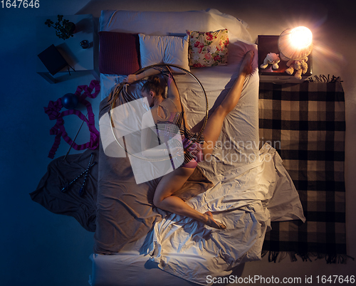 Image of Top view of young professional rhythmic gymnast sleeping at her bedroom in sportwear. Home interior.