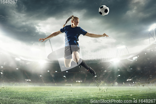 Image of Female football or soccer player kicking ball in jump at stadium - motion, action, activity concept. Flyer for ad, design.