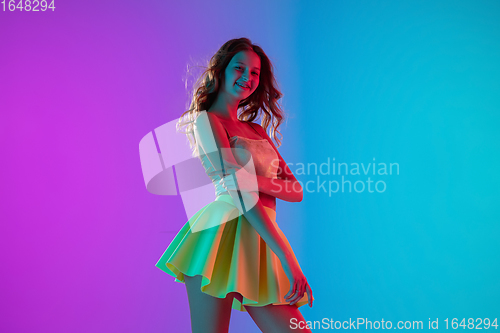 Image of Portrait of beautiful seductive girl in fashionable bright outfit on colour gradient pink-blue background in neon light.