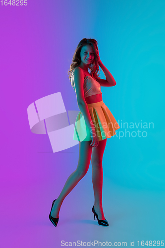 Image of Beautiful seductive girl in fashionable bright summer outfit posing on colour gradient pink-blue background in neon light.