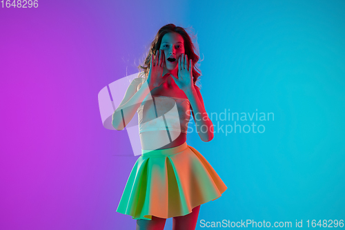 Image of Portrait of beautiful seductive girl in fashionable bright outfit on colour gradient pink-blue background in neon light.