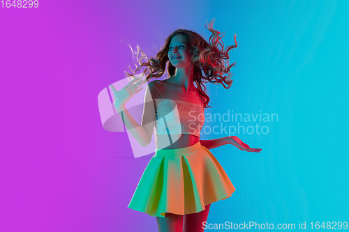 Image of Portrait of beautiful seductive girl in fashionable bright outfit on colour gradient pink-blue background in neon light.