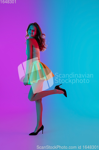 Image of Beautiful seductive girl in fashionable bright summer outfit posing on colour gradient pink-blue background in neon light.