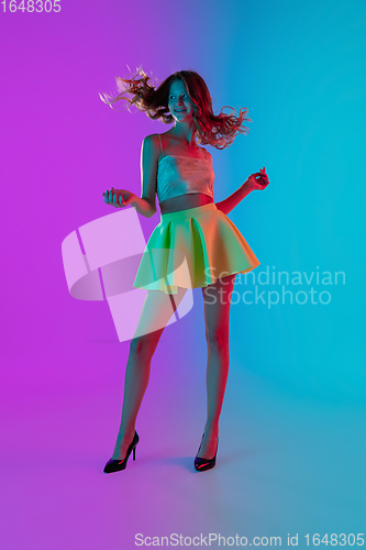 Image of Portrait of beautiful seductive girl in fashionable bright outfit on colour gradient pink-blue background in neon light.