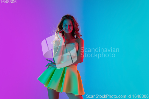 Image of Portrait of beautiful seductive girl in fashionable bright outfit on colour gradient pink-blue background in neon light.