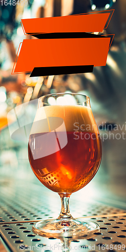 Image of Glass with foaming lager on bar rack. Vertical banner, flyer for ad.