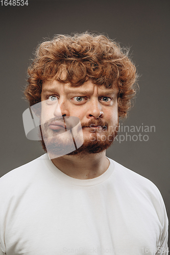 Image of Young man with dual emotions combination on face isolated on dark background, emotional and expressive