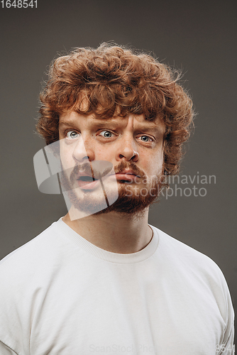 Image of Young man with dual emotions combination on face isolated on dark background, emotional and expressive