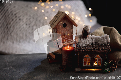 Image of Miniatures of houses isolated on grey and white background with garland lights. The concept of home atmosphere and comfort.