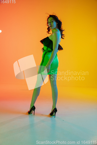 Image of Portrait of beautiful seductive girl in fashionable, modern outfit on bright gradient background in neon light
