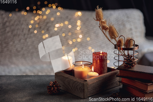 Image of Burning candles in the wooden box isolated on grey and white background with garland lights. Greeting card design.