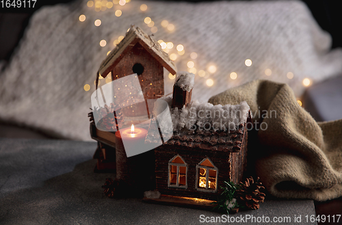 Image of Miniatures of houses isolated on grey and white background with garland lights. The concept of home atmosphere and comfort.