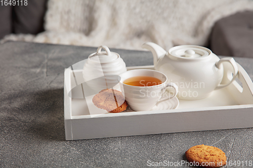 Image of White wooden tray with tea set on grey table. The concept of home atmosphere and comfort.