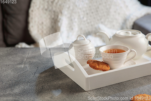 Image of White wooden tray with tea set on grey table. The concept of home atmosphere and comfort.