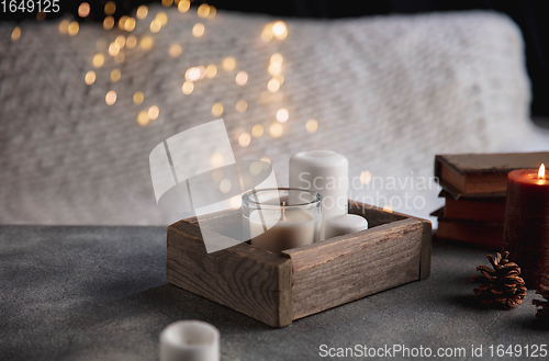 Image of Burning candles in the wooden box isolated on grey and white background with garland lights. Greeting card design.