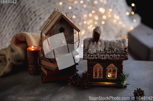 Image of Miniatures of houses isolated on grey and white background with garland lights. The concept of home atmosphere and comfort.