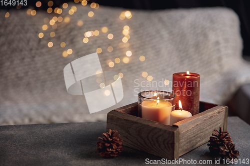 Image of Burning candles in the wooden box isolated on grey and white background with garland lights. Greeting card design.