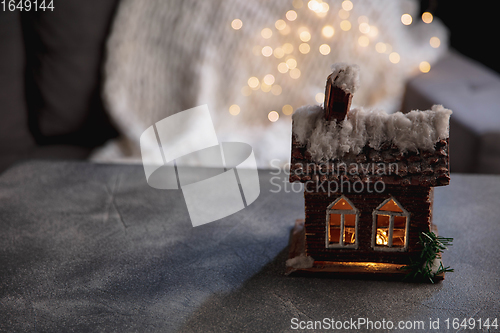 Image of House miniature illuminated against grey background. Cozy winter, snowing. Copy space for ad, design.