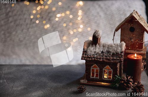 Image of Miniatures of houses isolated on grey and white background with garland lights. The concept of home atmosphere and comfort.