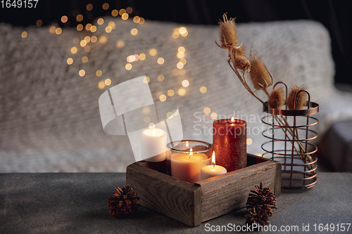 Image of Burning candles in the wooden box isolated on grey and white background with garland lights. Greeting card design.