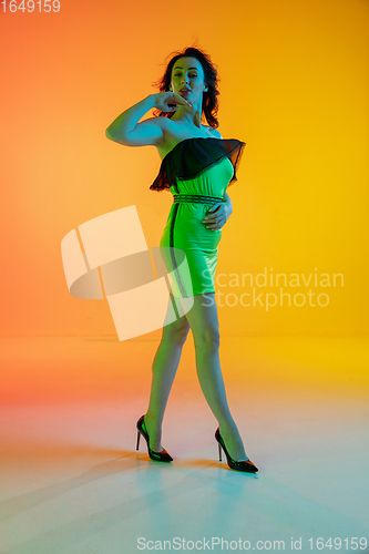 Image of Portrait of beautiful seductive girl in fashionable, modern outfit on bright gradient background in neon light