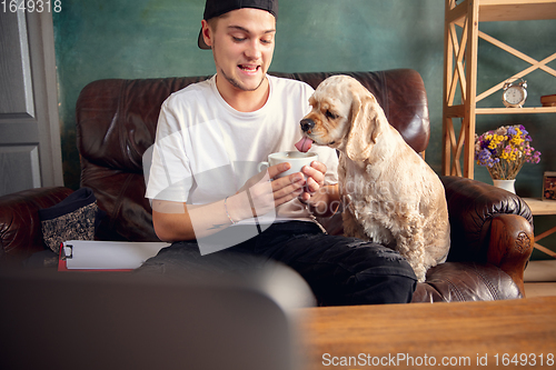 Image of Two best friends young man and American Cocker Spaniel cream colour drink tea at home.